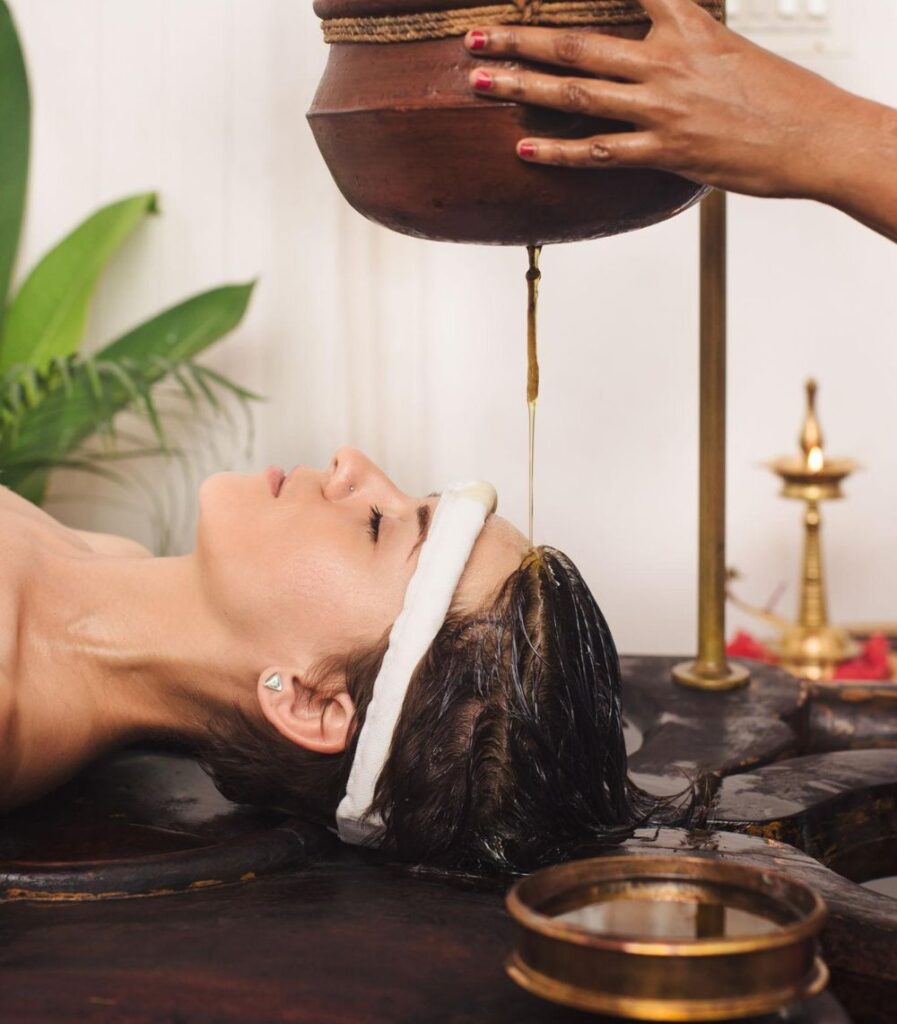 Traditional Kerala Ayurveda treatment with therapists applying warm oil to patient head